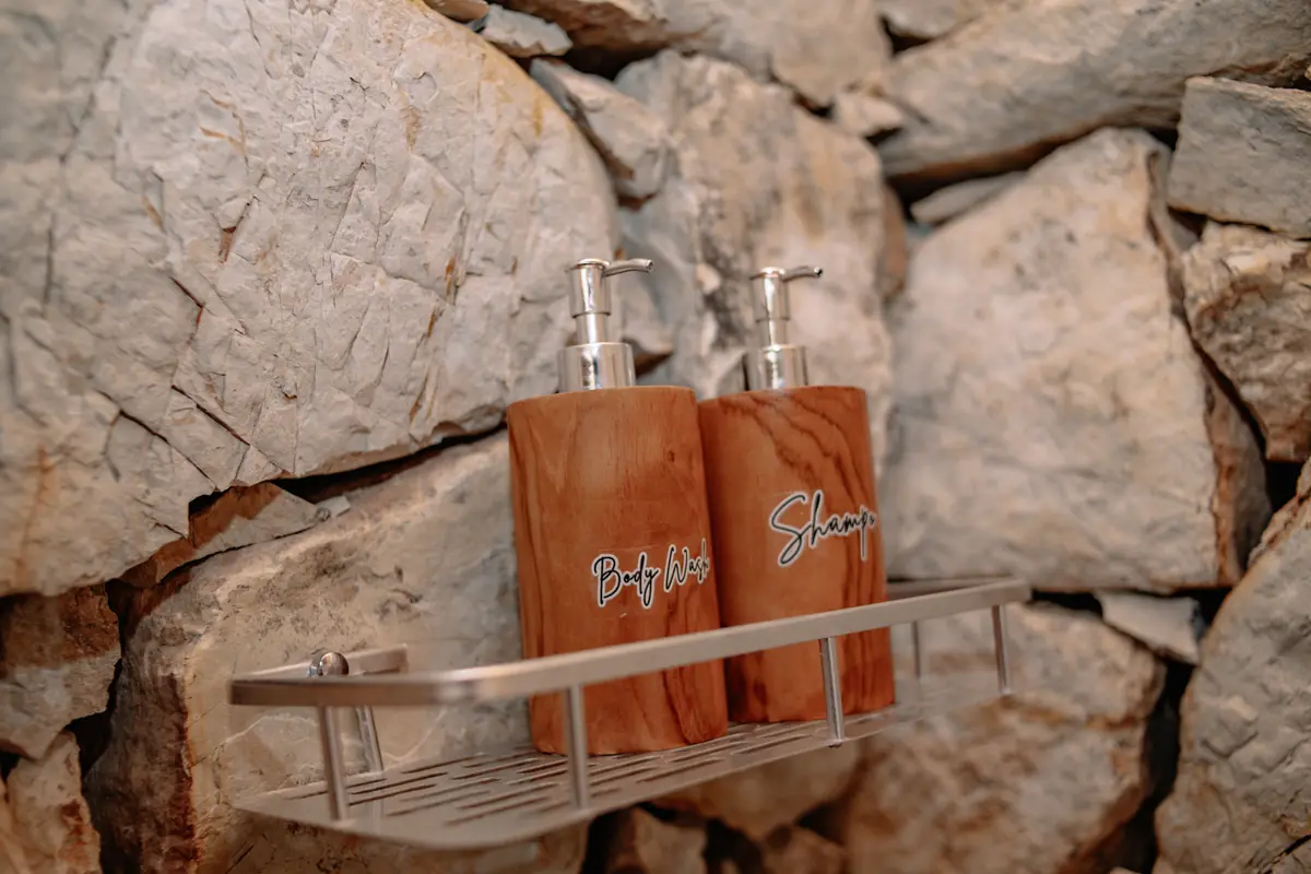 Shampoo and body wash dispensers on a stone shower wall