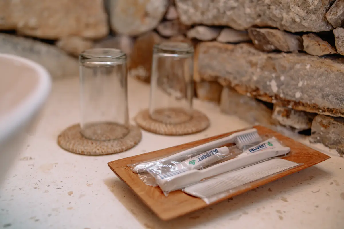 Glasses and toiletries on a teak tray beside the basin