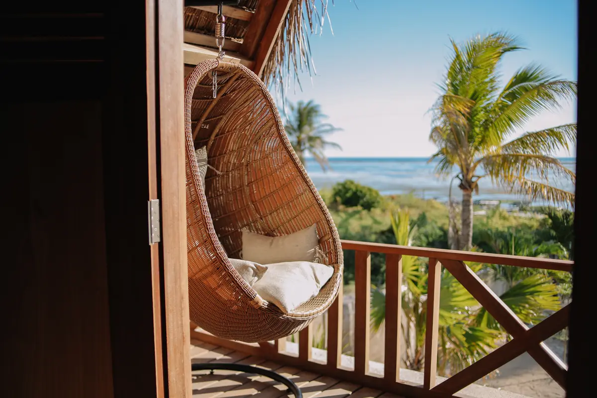 Hanging rattan chair on the Family Room balcony, palms and the ocean beyond