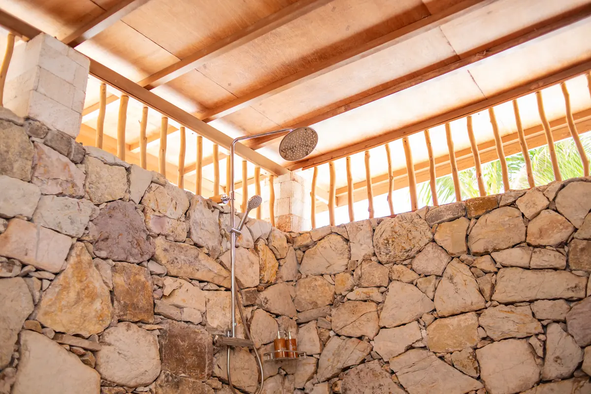 Rain shower in the stone-walled bathroom, open to the light above