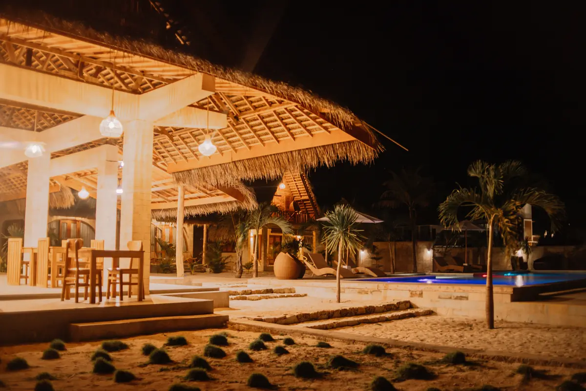The open thatched pavilion lit warm at night