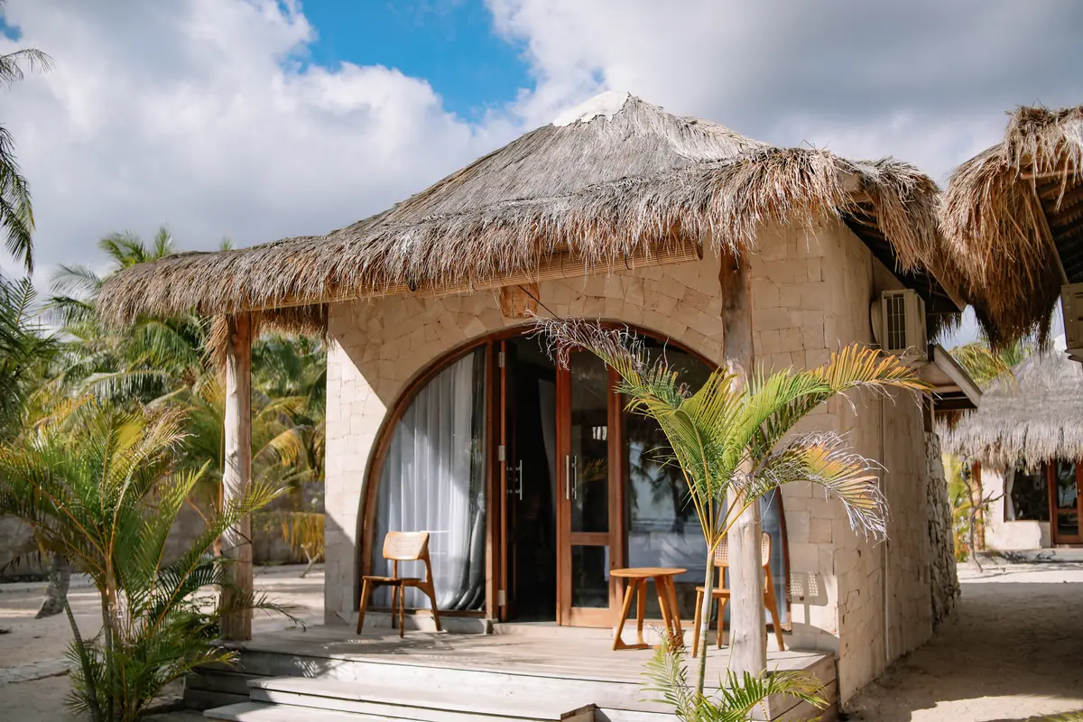 Limestone Oceanfront Room with thatched roof and arched teak doors