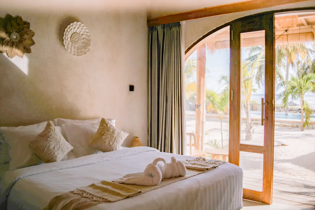 Oceanfront Room king bed with arched doors open to the pool and the sea