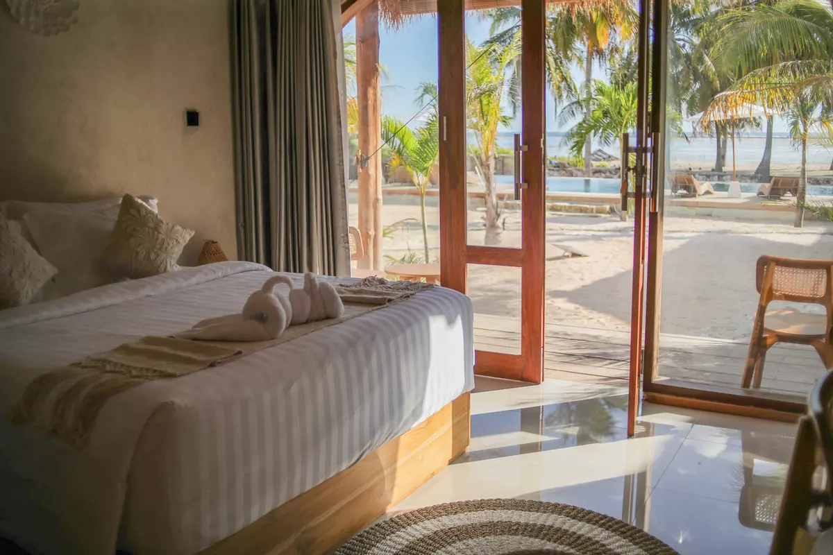 Glass doors of the Oceanfront Room open onto sand, palms and the ocean