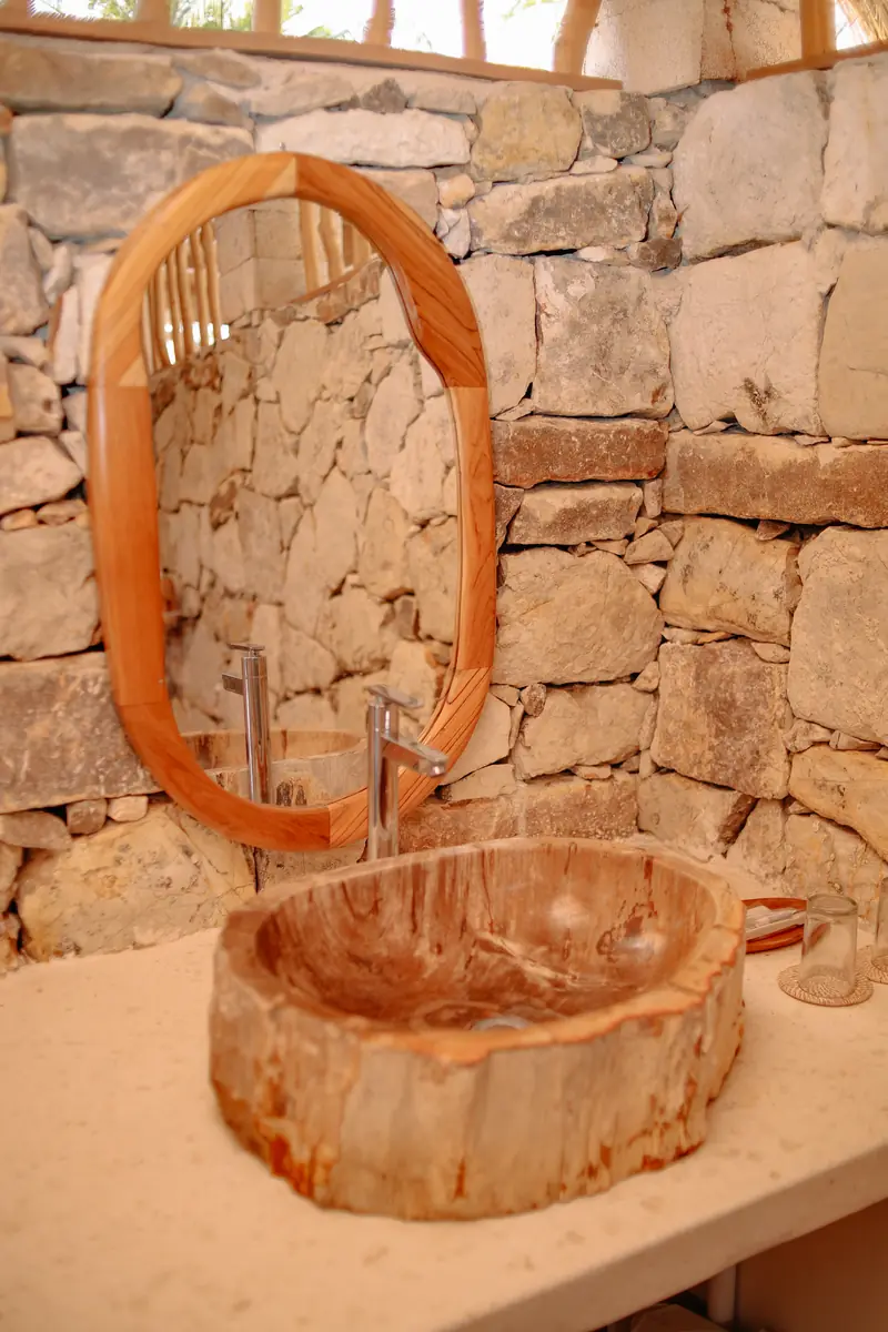 Carved stone basin and teak mirror in an Oceanfront Room bathroom