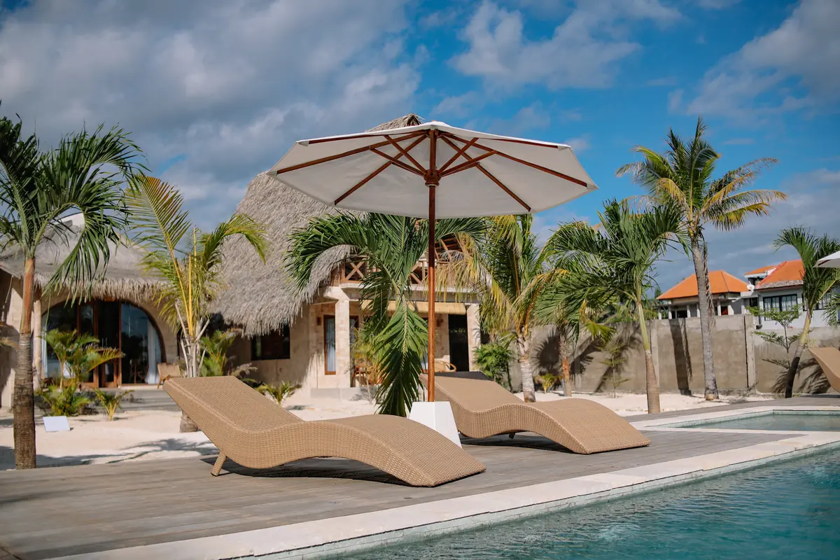 Wicker loungers under a canvas umbrella on the pool deck